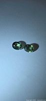 Pair of oval green sapphires on white background