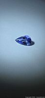 Pear-shaped violet-blue faceted Tanzanite on neutral background