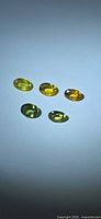 Five loose oval sapphires arranged on light surface