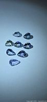 Eight pear-cut Tanzanites arranged on light background