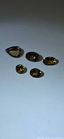 Five loose faceted gemstones on gray background