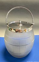 Front view showing frosted glass barrel body, silver-plated rim, lid, and handle