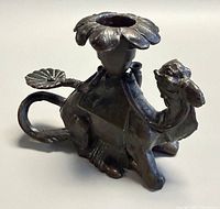Side view of cast metal camel candle holder showing detailing and flower cup