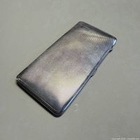 Front view of closed silver-plated cigarette case showing guilloché surface and cartouche