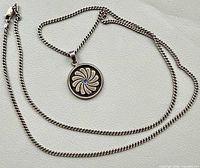 Necklace laid flat showing full 25" curb chain and round floral pendant