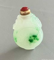 Front view of jade snuff bottle showing relief carving and green inclusions