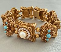 Bracelet in closed loop showing ornate links, clasp, faux pearl and turquoise stones