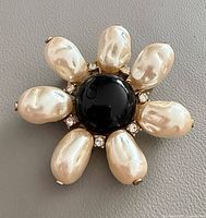 Front view showing faux pearl petals, black cabochon and rhinestone halo
