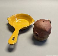 Mini yellow enameled skillet beside pig salt shaker