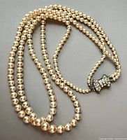 Coiled two-strand pearl necklace showing pearls and clasp