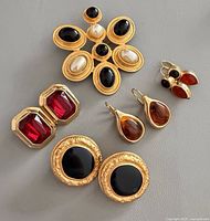 Group shot of brooch and four earring pairs on grey background