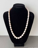 Necklace displayed on black bust showing full length and pearl uniformity