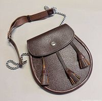 Front view of brown leather sporran showing tassels and snap closure