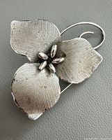 Front view of sterling silver flower brooch showing textured petal detail and stamen cluster
