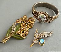 Bracelet, bouquet brooch, feather brooch side by side