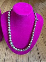 Full view of necklace on display bust showing bead strand and clasp