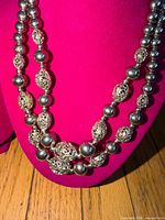 Front view of necklace on display bust showing two strands of silver-tone round and filigree beads