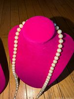 Full length of pearl necklace displayed on form