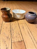 Three small pots side by side on wood floor