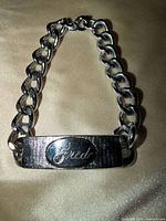 Front view of silver-tone ID bracelet showing engraved name and curb links
