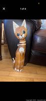 Full view of carved wooden cat standing on floor