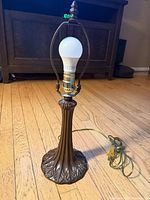 Full view of table lamp, showing base, column, harp, bulb and cord