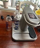 Bartesian drink maker with three Vodka bottles and accessories on tabletop