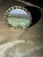 Front view of round silver-tone frame with multicolored stones and shamrock
