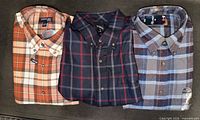 All three folded plaid shirts side by side