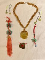Overview of entire lot showing necklace, tassel, charms, coin knot