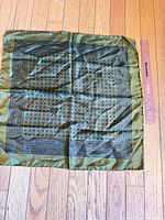 Full view of green patterned silk square scarf with ruler for scale