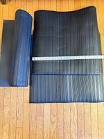 Three black ribbed mats, one rolled, tape measure showing width