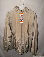 Front view of tan Calvin Klein jacket on hanger with tag attached
