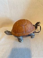 Top/front view of amber glass turtle lamp showing shell, metal legs, head and cord