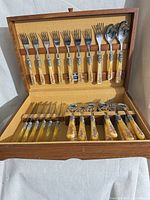 Full view of open wooden case showing all 35 flatware pieces in place