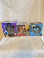 Front view of all three boxed vinyl figures