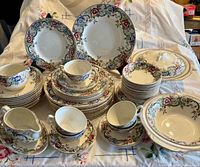 Overall view of stacked plates, bowls, cups, gravy boat, serving pieces in Seville pattern