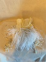 Front view showing beaded exterior, feather trim, tasselled drawstring