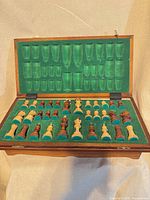 Open folding chess board showing green felt storage compartments and full set of pieces