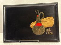 Full view of black Couroc tray showing inlaid bread, wine carafe and script