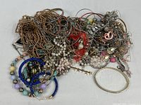 pile of tangled costume jewelry showing variety of necklaces, bracelets, beads