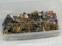 Overall view of plastic tub filled with assorted costume jewelry pieces