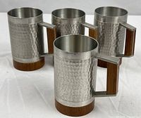 Four hammered pewter mugs with wood bases and handles