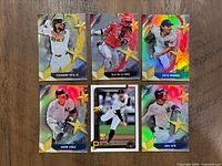 Front view of all six 2025 Topps Series One cards laid on wooden surface showing player images, names and star designs