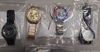 Group image of four wristwatches in clear bags