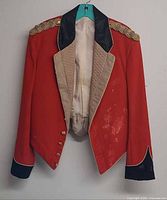 Front view showing red tailcoat, black collar/cuffs, gold braid epaulettes, buttons, visible stains