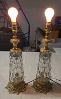Both lamps illuminated showing glass columns and brass bases