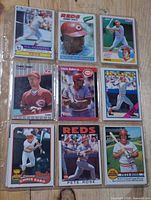 Nine baseball cards in plastic sheet featuring Reds players including Pete Rose and Chris Sabo
