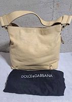 Front view of butter yellow shoulder bag with black Dolce & Gabbana dust bag
