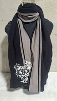 Full view of scarf on mannequin showing black and gray design and crest graphic